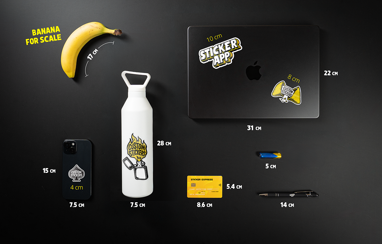Size guide for stickers. Various items on a black surface with measurements: banana, water bottle, laptop, phone, card, pen, knife, and stickers.