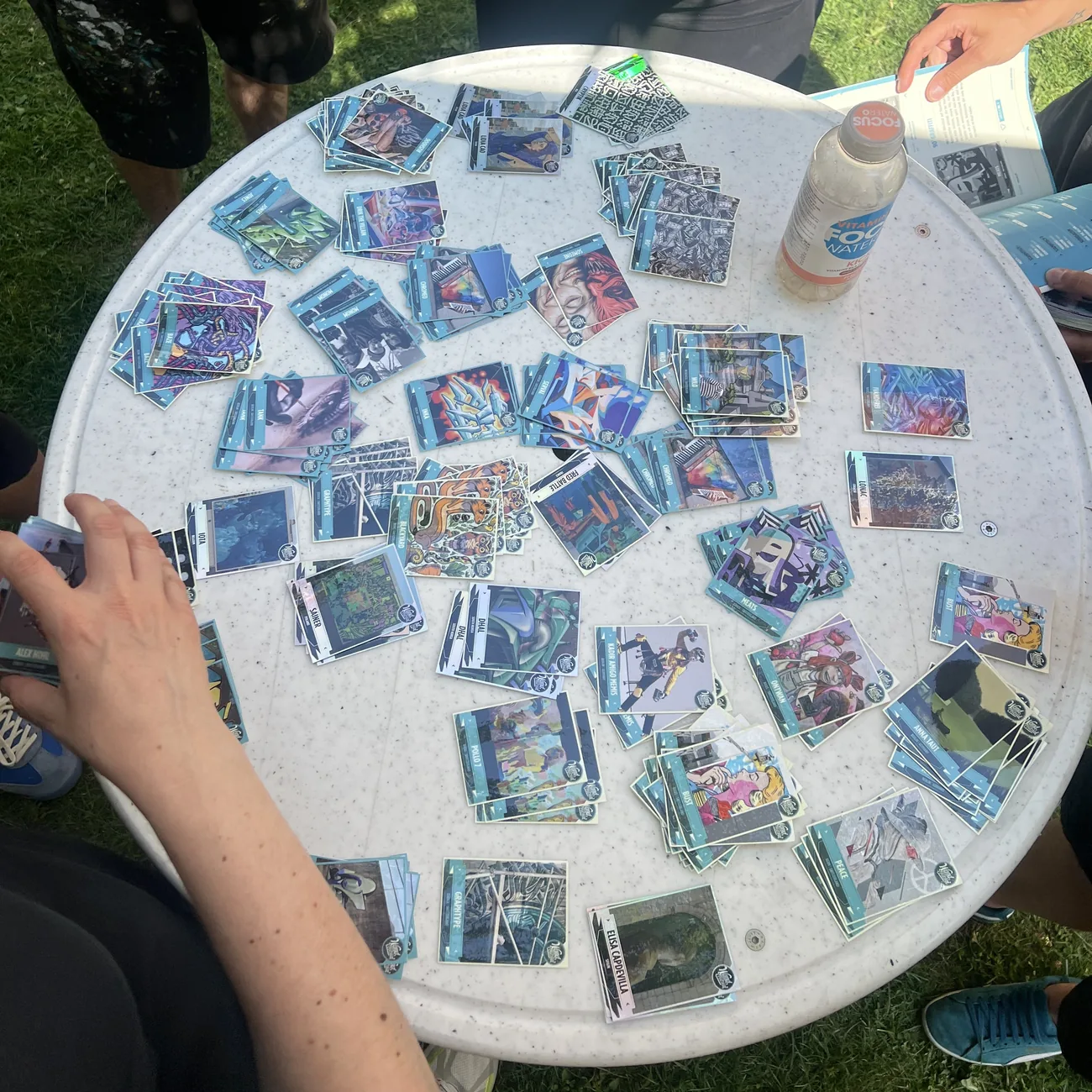 Uczestnicy festiwalu wypełniają niebieskie albumy kolekcjonerskimi naklejkami ze street artem rozłożonymi na okrągłym stole
