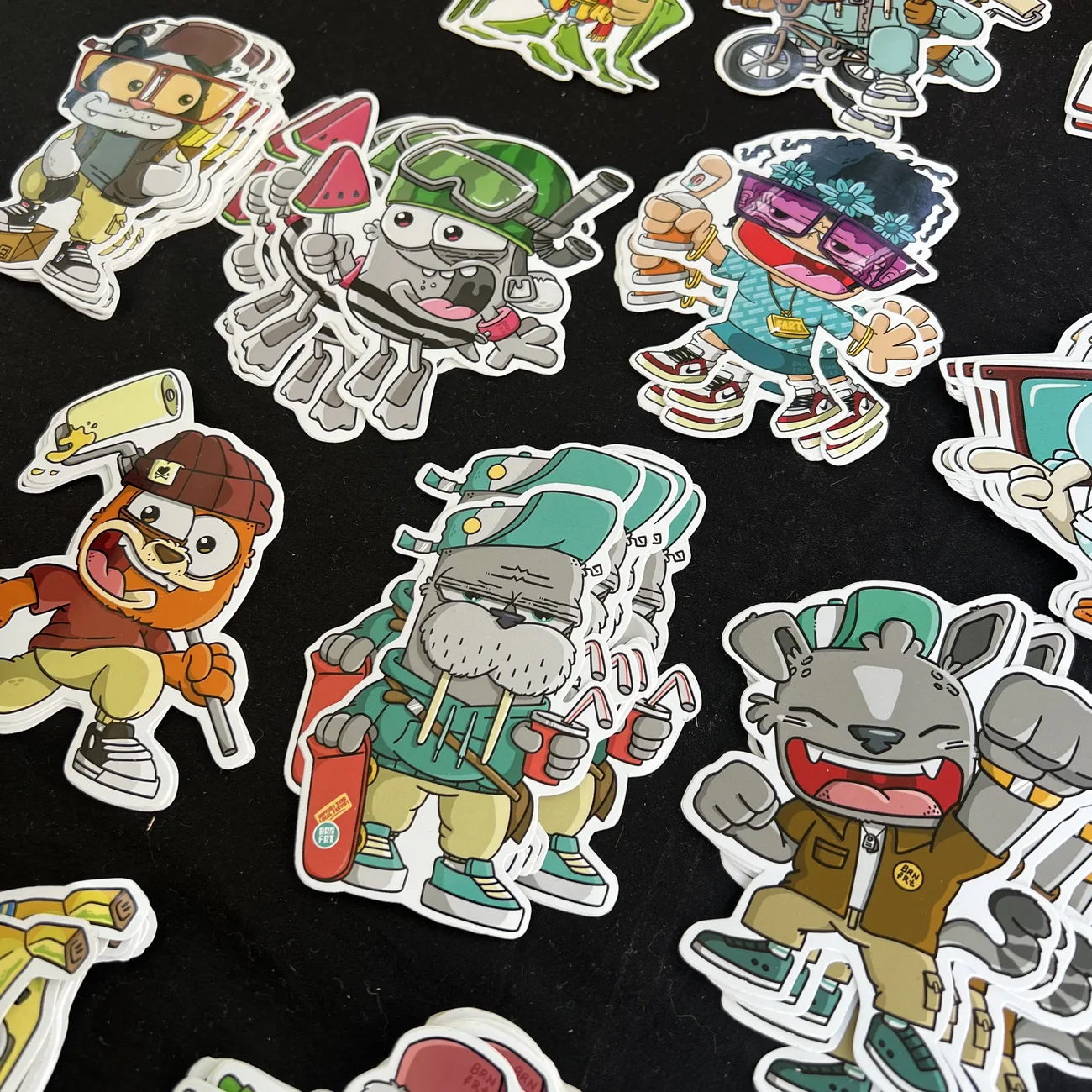 Naklejki wycinane do kształtu Brainfart x StickerApp z kreskówkowymi postaciami w streetwearze, m.in. morsem z deskorolką i uśmiechniętym kotem