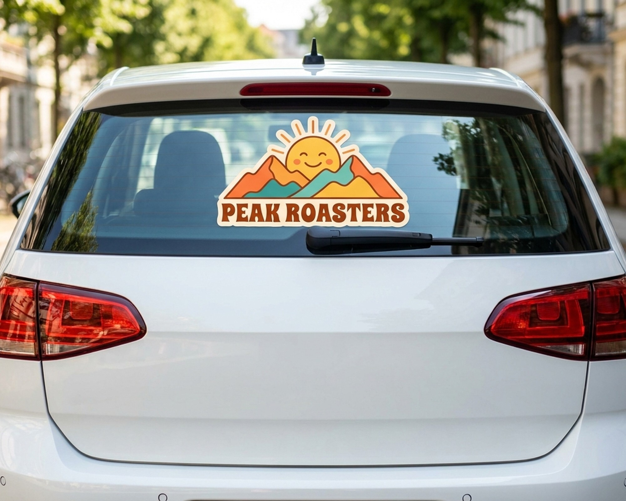 Personalizowana kalkomania wycinana po obrysie z logo słońca i gór oraz napisem „Peak Roasters” na tylnej szybie samochodu