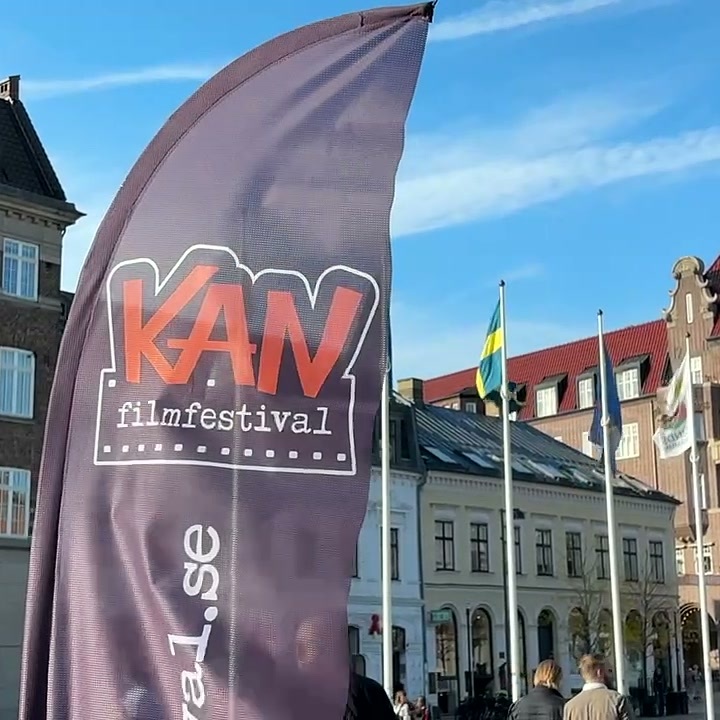 Flaga reklamowa KAN Film Festival na tle zabytkowych budynków i flag na placu w Lund