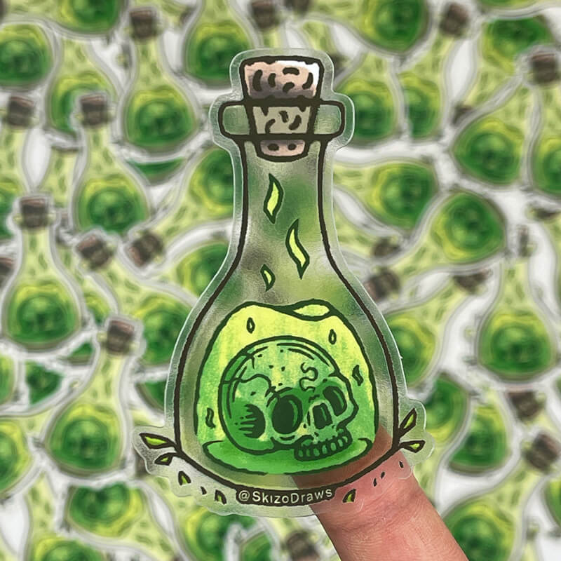 Transparentna naklejka wycinana po obrysie z czaszką unoszącą się w butelce z zielonym eliksirem, na tle naklejek.