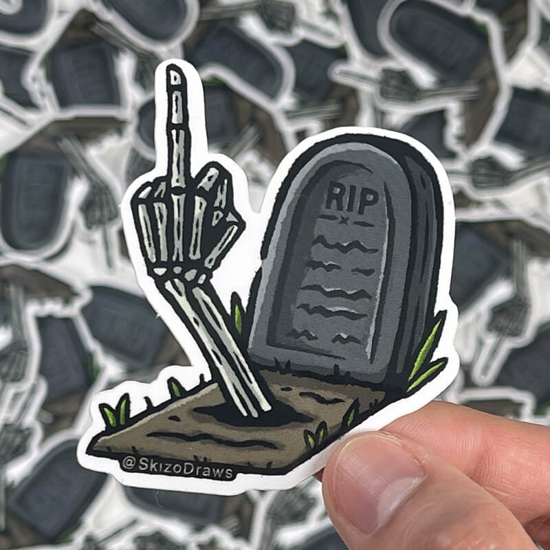 Winylowa naklejka wycinana po obrysie z nagrobkiem z napisem „RIP” i ręką szkieletu, która wystaje z ziemi i pokazuje środkowy palec, na tle naklejek.